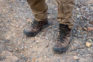 Man with hiking boots on standing on top of gravel. 
