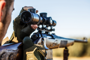 Man looking through the sight on his rifle while hunting. 