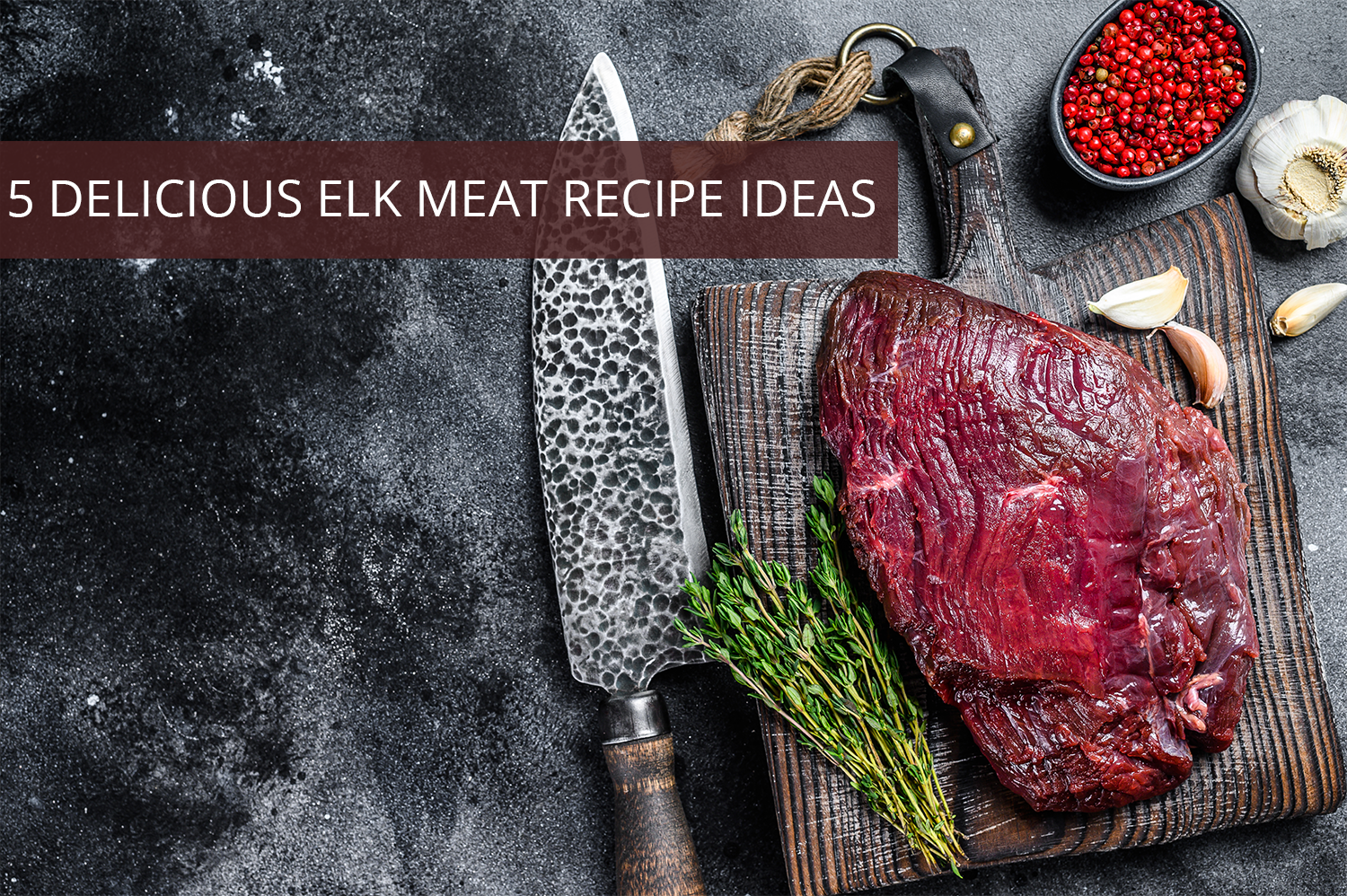 Elk meat on a wooden board with red pepper corns, a garlic bulb, fresh greens herbs, and a knife next to it.