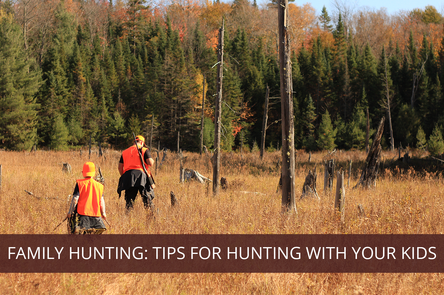 Man and son in Colorado walking through grass with orange vests and hats on during family hunting trip