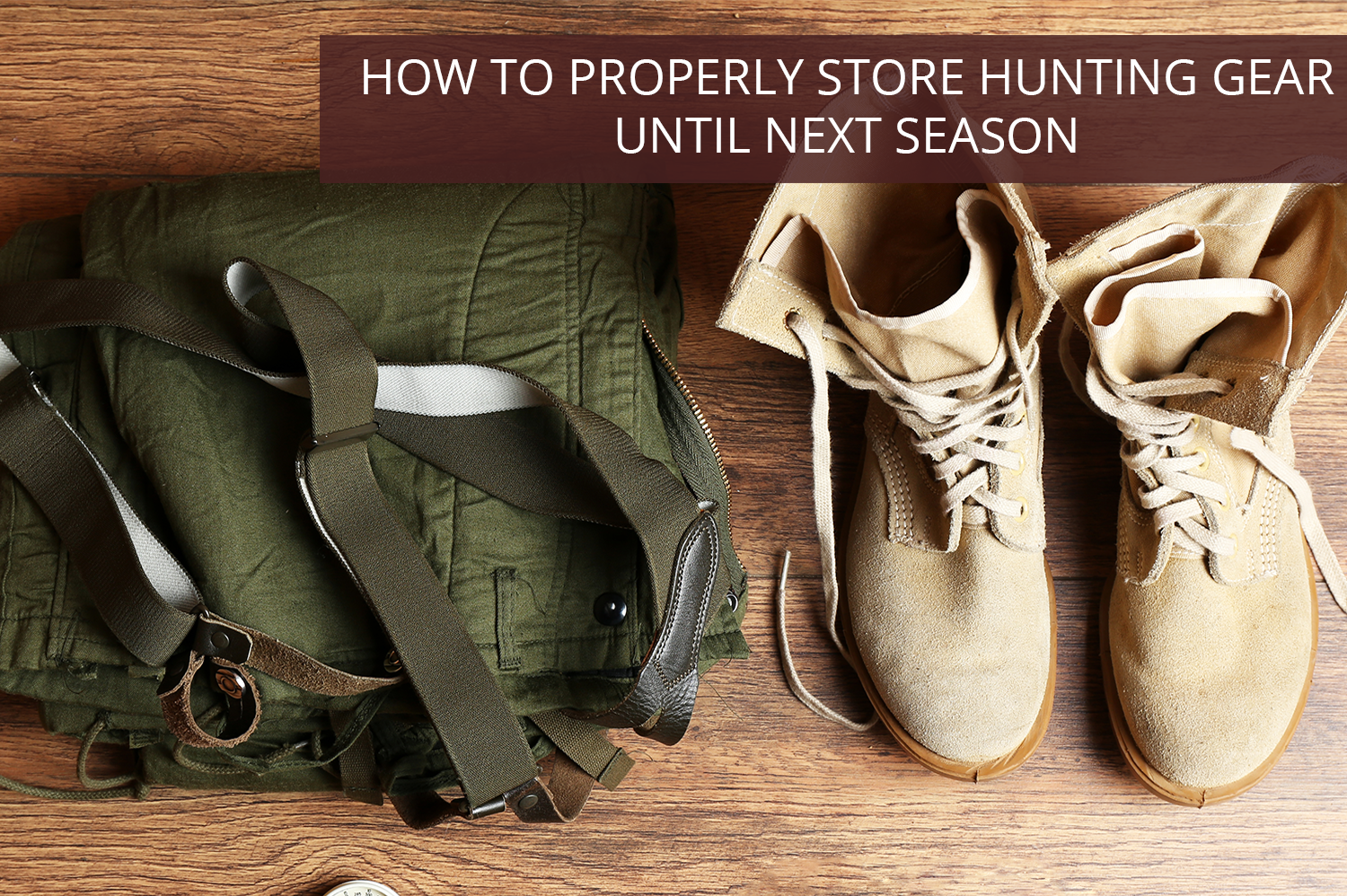 A pile of hunting gear - green pants and suspenders and beige boots - sitting on a brown wooden floor.