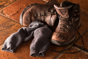 Brown hunting gear boots with gray socks on a brown tile floor.