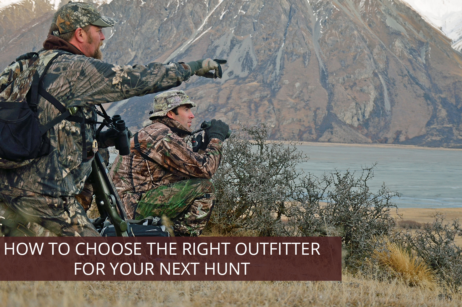 An outfitter pointing out an elk to a hunter.